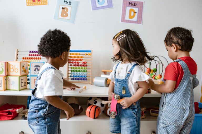 Trois enfants en bas age portent une salopette en jean bleu.