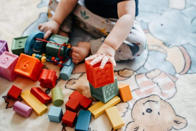 un bébé joue avec des cubes sur un tapis coloré